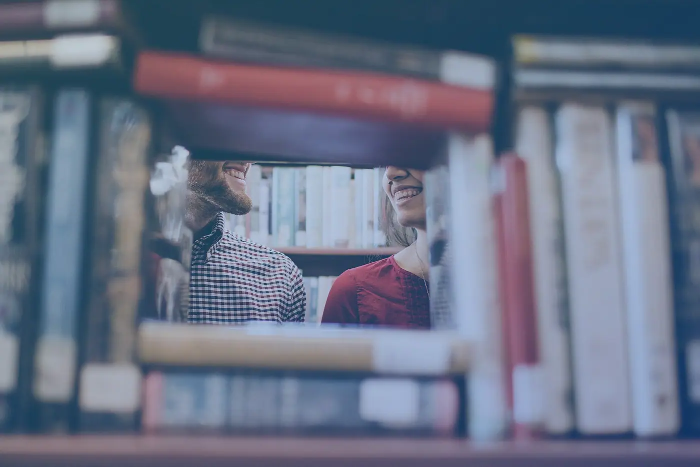 Students reading among library shelves